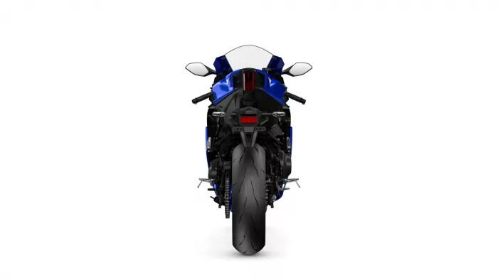 Rear view of a blue sport motorcycle on a white background, showing taillight and wide tire.