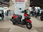 Yamaha motorcycle showroom with red and black scooter in the foreground and several bikes on display in the background.