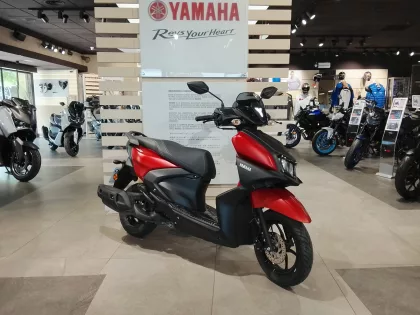 Yamaha motorcycle showroom with red and black scooter in the foreground and several bikes on display in the background.
